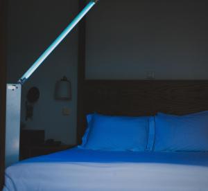 - une chambre dotée d'un lit bleu avec une lumière au-dessus dans l'établissement Keros Art Hotel, à Koufonisia