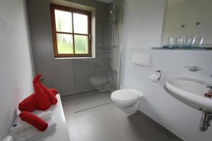 a white bathroom with a red stuffed animal on a counter at Haus Bergblick in Rieden