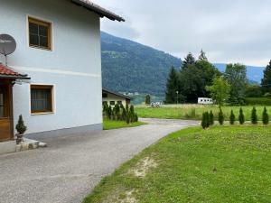 eine Straße neben einem weißen Haus mit einem Berg in der Unterkunft Ossiach Apartment 1 in Heiligen Gestade