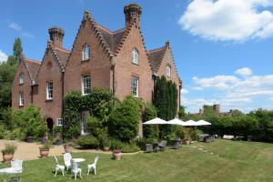 um grande edifício de tijolos com cadeiras e guarda-sóis no quintal em Sissinghurst Castle Farmhouse em Sissinghurst