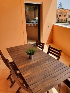 une table en bois avec des chaises et une plante en pot. dans l'établissement Praia da Luz Mar e Sol Apartamento, à Luz