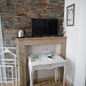 uma mesa branca com uma televisão em cima de uma lareira em Une affaire de famille em Le Portel