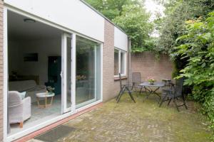 d'une terrasse avec des portes en verre, une table et des chaises. dans l'établissement Knus tuin-appartement vlakbij Nijmegen voor 2 personen, à Molenhoek