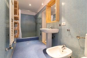 W wyłożonej niebieskimi kafelkami łazience znajduje się umywalka i toaleta. w obiekcie Veneziacentopercento Campaniel Apartment w Wenecji