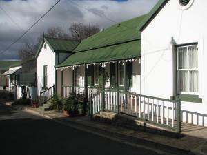 a white house with a green roof with christmas lights at Toverberg Guest Houses in Colesberg