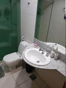 a bathroom with a sink and a toilet and a mirror at FLAT BIARRITZ SETOR HOTELEIRO NORTE QUARTO 106 in Brasília