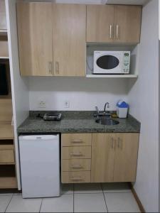 a small kitchen with a sink and a microwave at FLAT BIARRITZ SETOR HOTELEIRO NORTE QUARTO 106 in Brasília