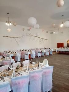 a large room with white tables and white chairs at Penzion Pivovar Podlesí in Příbram