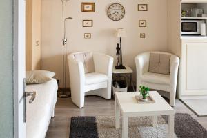 a living room with two white chairs and a table at Chic En Ville in Metz