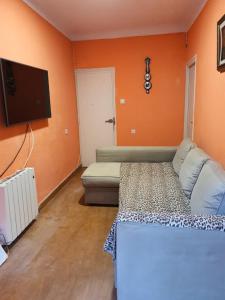 una camera da letto con pareti arancioni, divano e TV di aparment puerto Alto a Madrid
