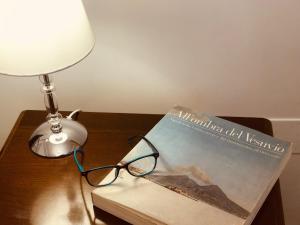 ein Buch auf einem Tisch mit einer Lampe und einer Brille in der Unterkunft Casa Chiara Italia luxury central free parking in Neapel
