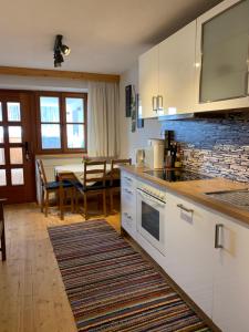 a kitchen with white cabinets and a dining table at Ferienwohnung am Wirtlerhof in Wildermieming