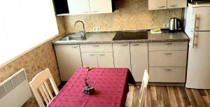 a kitchen with a table with a pink table cloth at Vasaros apartamentas Nr3 in Palanga