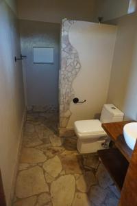 a bathroom with a toilet and a sink at Kikonko Lodge in Buseruka