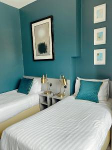 two beds in a room with blue walls at Rose Lodge Guest House in Cork