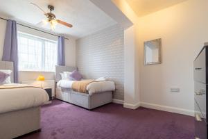 a bedroom with two beds and a ceiling fan at Spacious House for Contractors with plenty of street parking by Great Northampton Stays in Kingsthorpe
