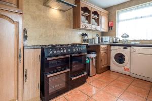 a kitchen with a stove and a washer and dryer at Spacious House for Contractors with plenty of street parking by Great Northampton Stays in Kingsthorpe