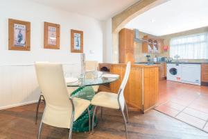 a kitchen with a glass table and white chairs at Spacious House for Contractors with plenty of street parking by Great Northampton Stays in Kingsthorpe