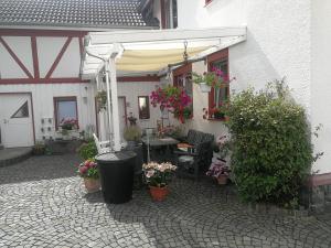 eine Außenterrasse mit einem Tisch, Stühlen und Blumen in der Unterkunft Ferienwohnung Bender in Gemünden