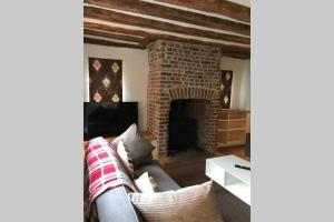 a living room with a couch and a brick fireplace at Stunning Cottage in Picturesque Village in Radlett