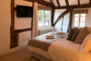a bedroom with a bed with a tv on the wall at Stunning Cottage in Picturesque Village in Radlett