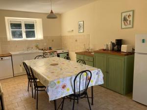 una cucina con tavolo, sedie e frigorifero di Gîte Aux chênes a La Viardière