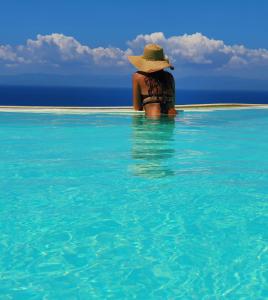 a woman in a hat sitting in the water at Vista mozzafiato a picco sul mare Villa Patty in Torre delle Stelle