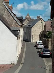 een steegje met auto's geparkeerd op een straat met gebouwen bij Chez charline in Sainte-Mère-Église