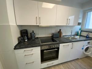 cocina con armarios blancos, fregadero y lavavajillas en Apartment im Zentrum en Kassel