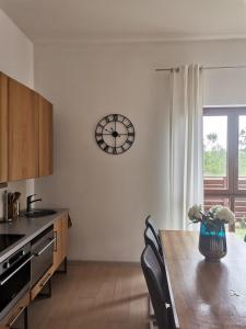 a kitchen with a table and a clock on the wall at LUX Apartment KARINA in Dziwnówek