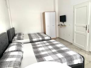 sypialnia z dwoma łóżkami, telewizorem i drzwiami w obiekcie Guest House Ondine w mieście Shëngjin
