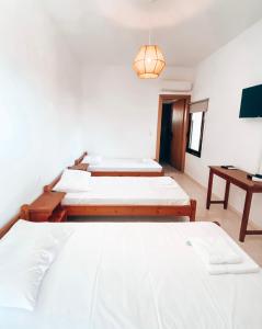 een kamer met drie bedden en een tafel bij Elafonisi Rooms For Rent in Elafonisi +46 foto's