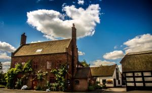 an old brick building with a cloud in the sky at Hundred House Hotel in Ironbridge