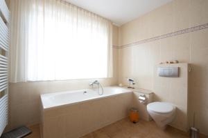 a bathroom with a tub and a toilet and a window at Feriendomizil Hönow in Hoppegarten +53 photos