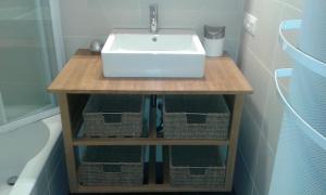 a bathroom with a sink and baskets under it at Lautrec in Bredene