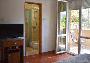 a bathroom with a television and a shower with a glass door at Apartments Montenegro Risan Čučković in Risan