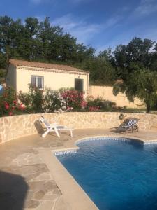 - une piscine avec 2 chaises et une maison dans l'établissement Gite les Bleuets, à Saze