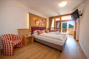 - une chambre avec un lit, une télévision et une chaise dans l'établissement Astor Suites B&B, à Selva di Val Gardena