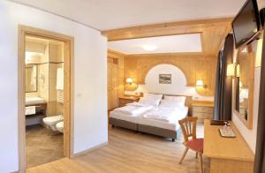 a hotel room with a bed and a desk and a chair at Astor Suites B&B in Selva di Val Gardena