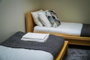 two beds in a room with white sheets and pillows at Copper Oven apartments in Arbroath