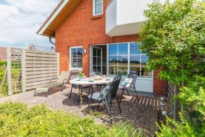 a patio with a table and chairs in front of a house at NTBM36001-Binnenseeblick in Neue Tiefe Fehmarn