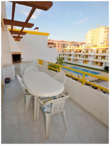 a white table and chairs on the roof of a building at Apartamentos Capitolina in Quarteira
