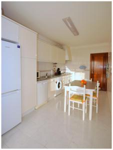 - une cuisine avec des appareils blancs, une table et des chaises dans l'établissement Apartamentos Capitolina, à Quarteira