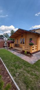 ein Holzhaus mit einer Veranda und einem Hof in der Unterkunft APARTAMENT DOMEK CAŁOROCZNY in Ciechocinek