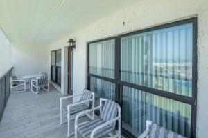 balcón con sillas, mesa y ventanas en Saida, en South Padre Island