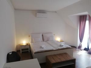 een slaapkamer met een bed met witte lakens en kussens bij Levanda Panzió in Kópháza