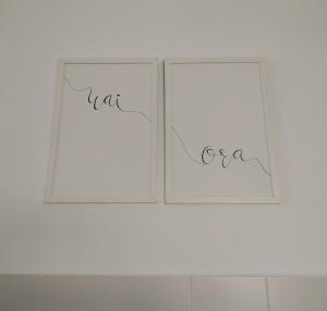 two white framed photographs on a white wall at Apartamento Waiora in Aguaviva