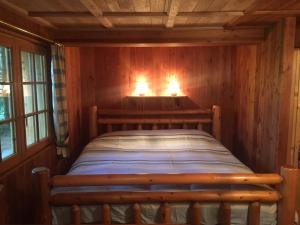 Una cama en una habitación de madera con dos luces. en L'Atelier, en Les Contamines-Montjoie