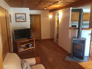 ein Wohnzimmer mit einem Holzofen und einem TV in der Unterkunft L'Atelier in Les Contamines-Montjoie