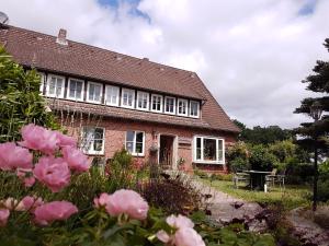una casa de ladrillo con rosas rosas delante de ella en Ferienhof Cohrs, en Bispingen
